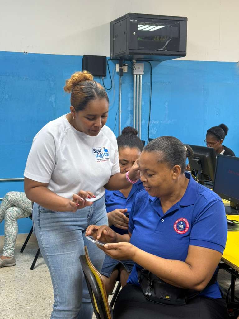 Señora adulta aprende a usar su celular acompañada por una facilitadora de Soy Digital